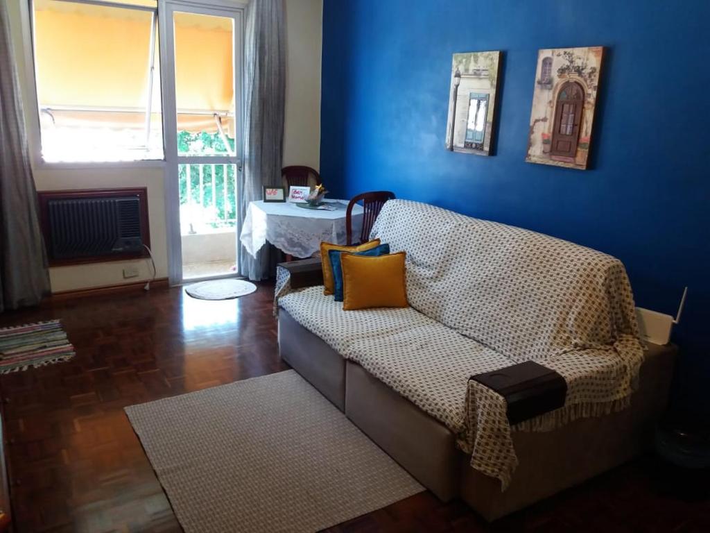 uma sala de estar com um sofá e uma parede azul em Aconchego da te no Rio de Janeiro