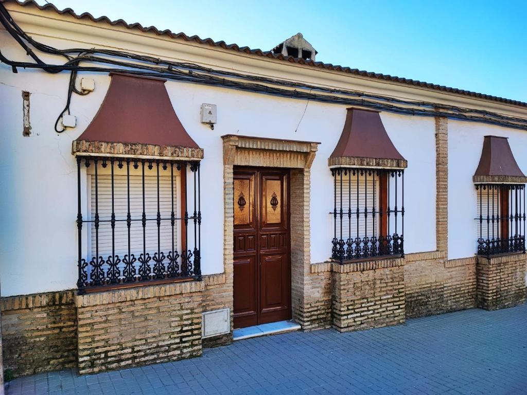 un edificio bianco con una porta marrone e due finestre di Casa Almadén 1 a Castilblanco de los Arroyos