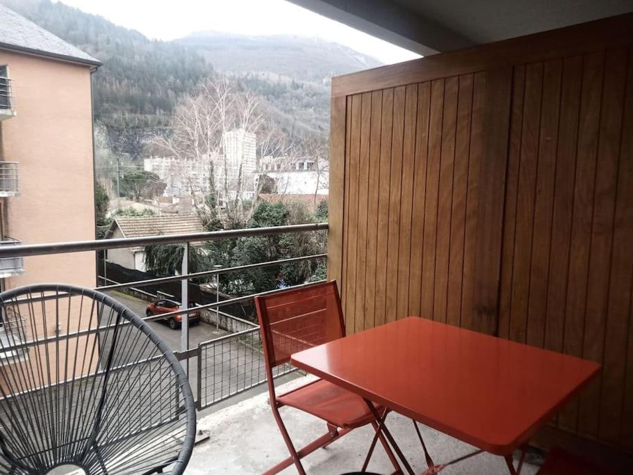 d'une table et d'une chaise rouges sur un balcon avec vue. dans l'établissement joli appartement T2 très bien situé, parking couvert, à Lourdes