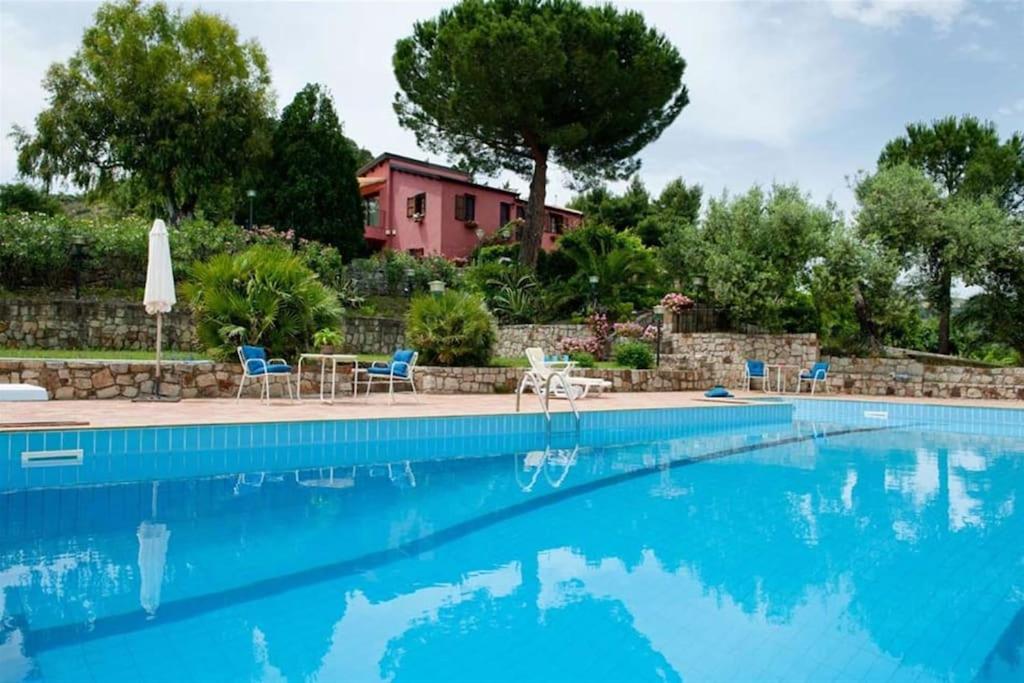 a swimming pool with chairs and a house in the background at Villa Ivoni 1 in Campofelice di Roccella