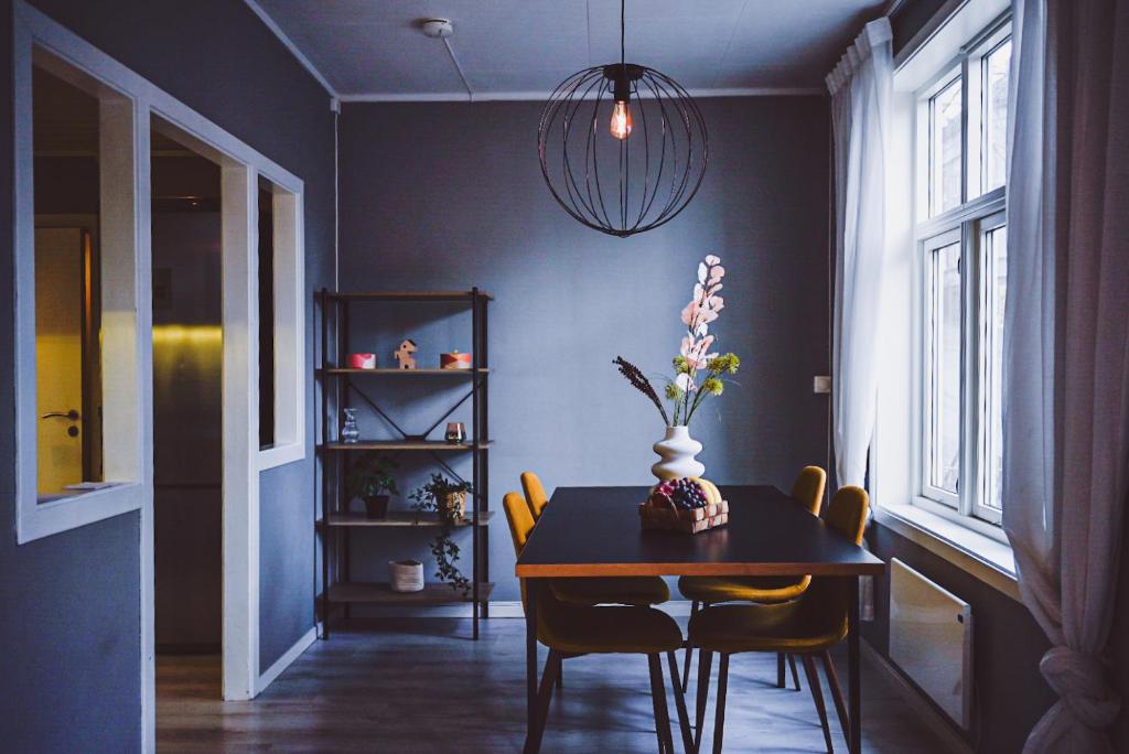 una mesa de comedor con sillas y un jarrón de flores. en Moderne leilighet ved Solsiden i Trondheim, en Trondheim