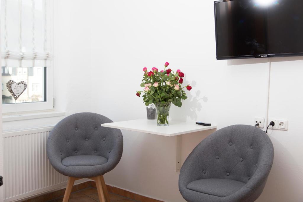 two chairs and a table with a vase of flowers at Pension Gästehaus La Mula in Treis-Karden