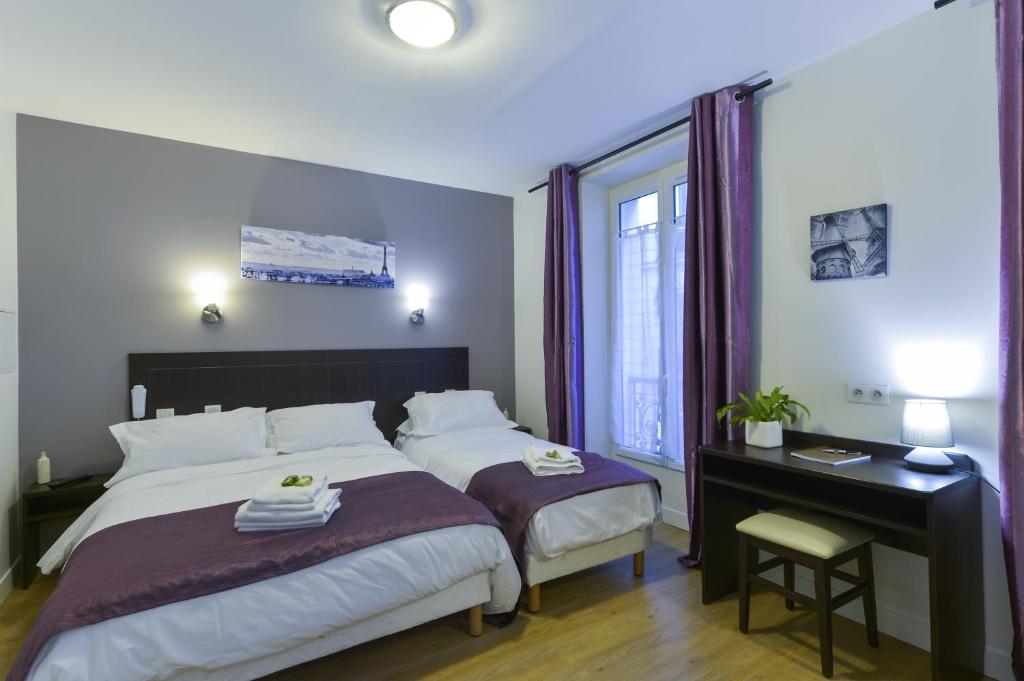 a bedroom with a bed and a desk and a window at Hôtel du Quai de Seine in Paris