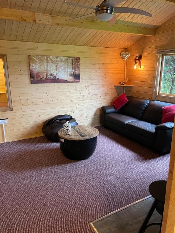 a living room with a couch and a table at Cosy 2 BR cabin on coast private hot tub ' Driftwood ' in Stolford