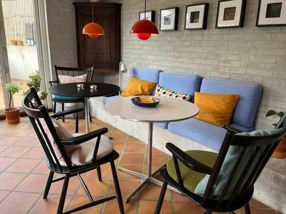 een woonkamer met een bank en een tafel en stoelen bij Skønne værelser med adgang til pejsestue og have in Risskov
