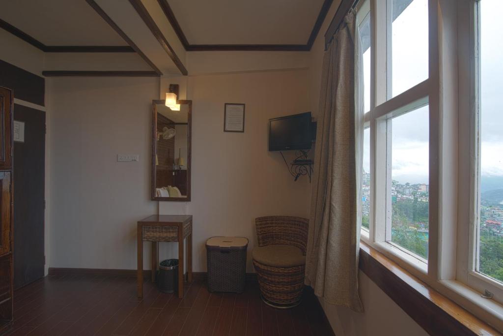 a living room with a large window with a view at The Nettle and Fern Hotel Gangtok in Gangtok