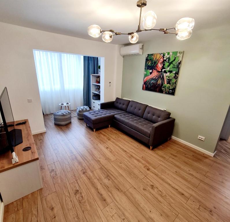 sala de estar con sofá de cuero negro y suelo de madera en Eden Apartment, en Cluj-Napoca