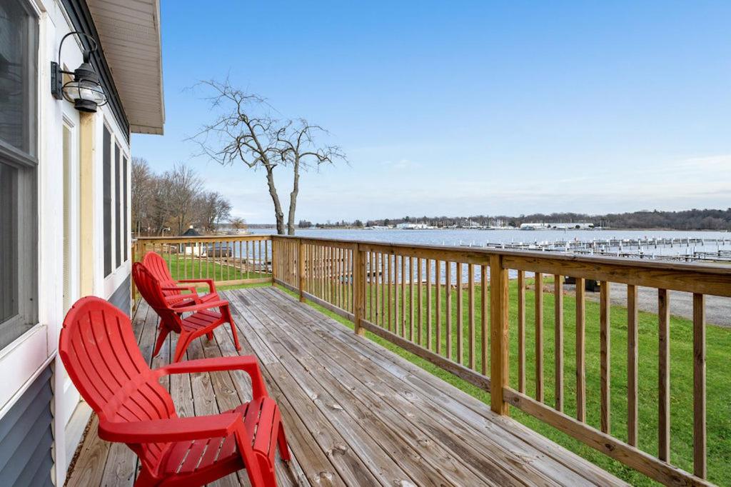 três cadeiras vermelhas sentadas no alpendre de uma casa em Lakeside House by Michigan Waterfront Luxury Properties em Montague