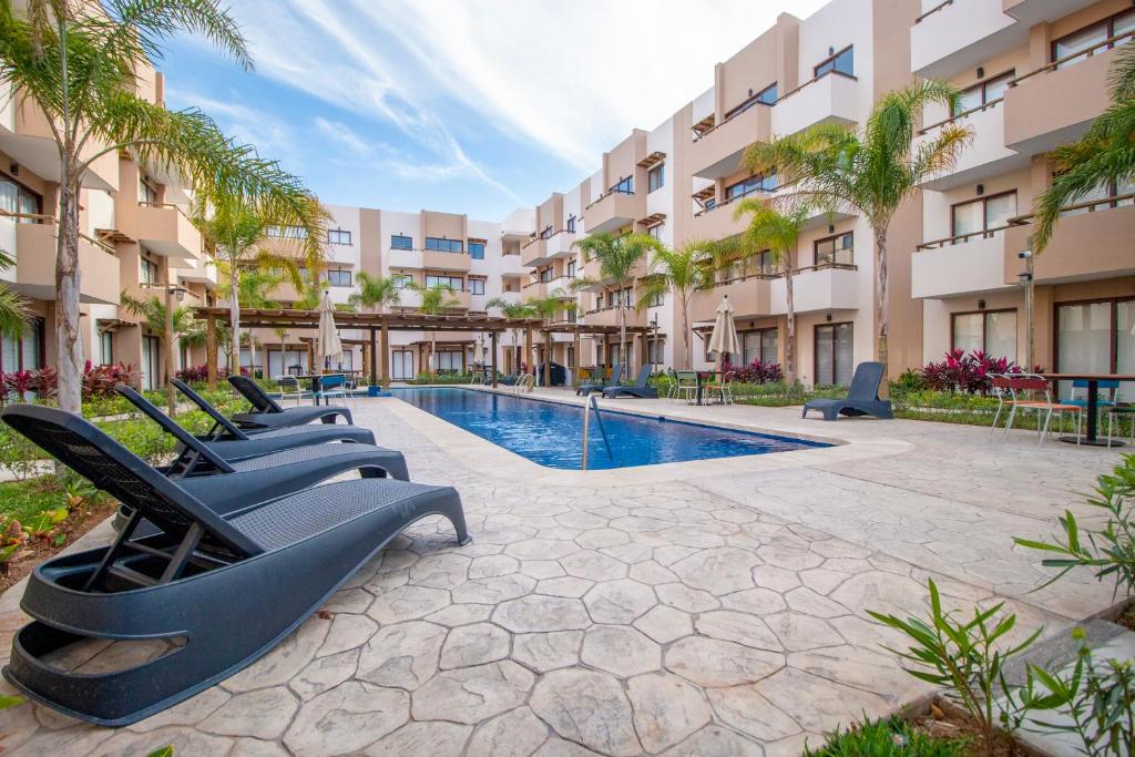 una piscina resort con tumbonas y palmeras en Ambar Condominios Mazatlan, en Mazatlán