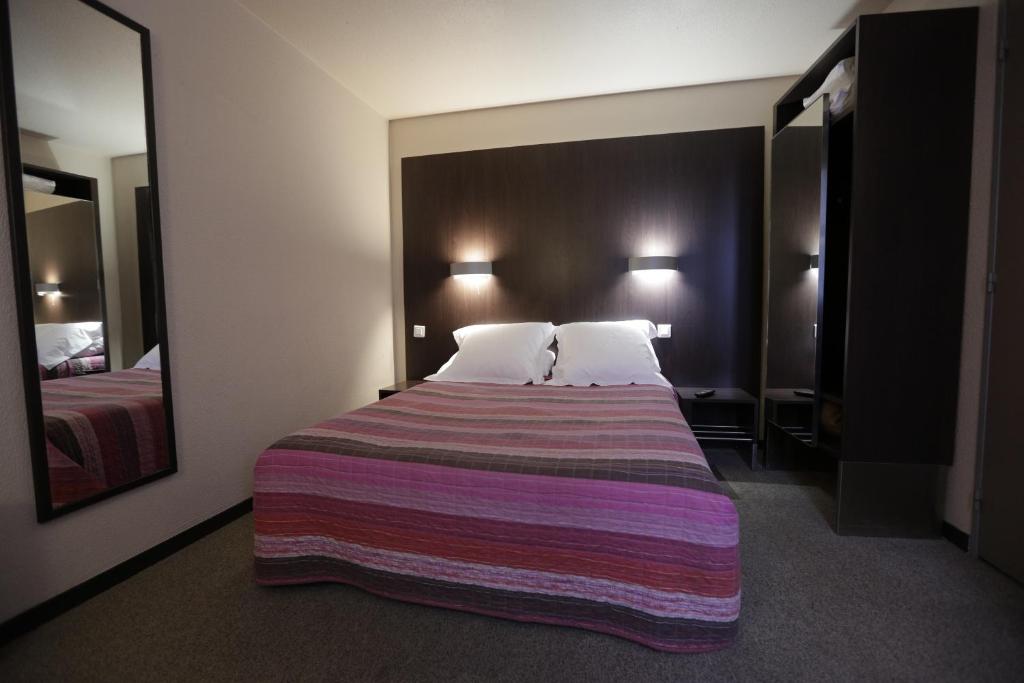 um quarto de hotel com uma cama grande com um cobertor listrado em Hôtel Au Petit Caporal em Maisons-Alfort