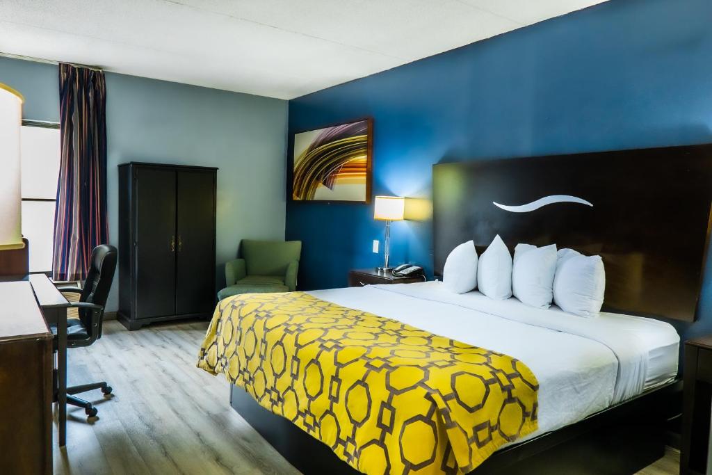 a hotel room with a large bed with a yellow blanket at Baymont by Wyndham London KY in London