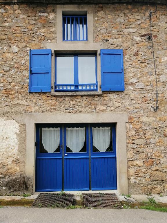 une porte bleue et deux fenêtres dans un bâtiment en pierre dans l'établissement Charmante petite grange - 5 Couchages, à Nalzen