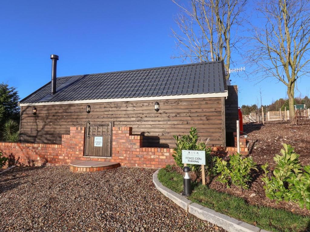 a small brick building with a sign in front of it at Foxes Den in Scarborough