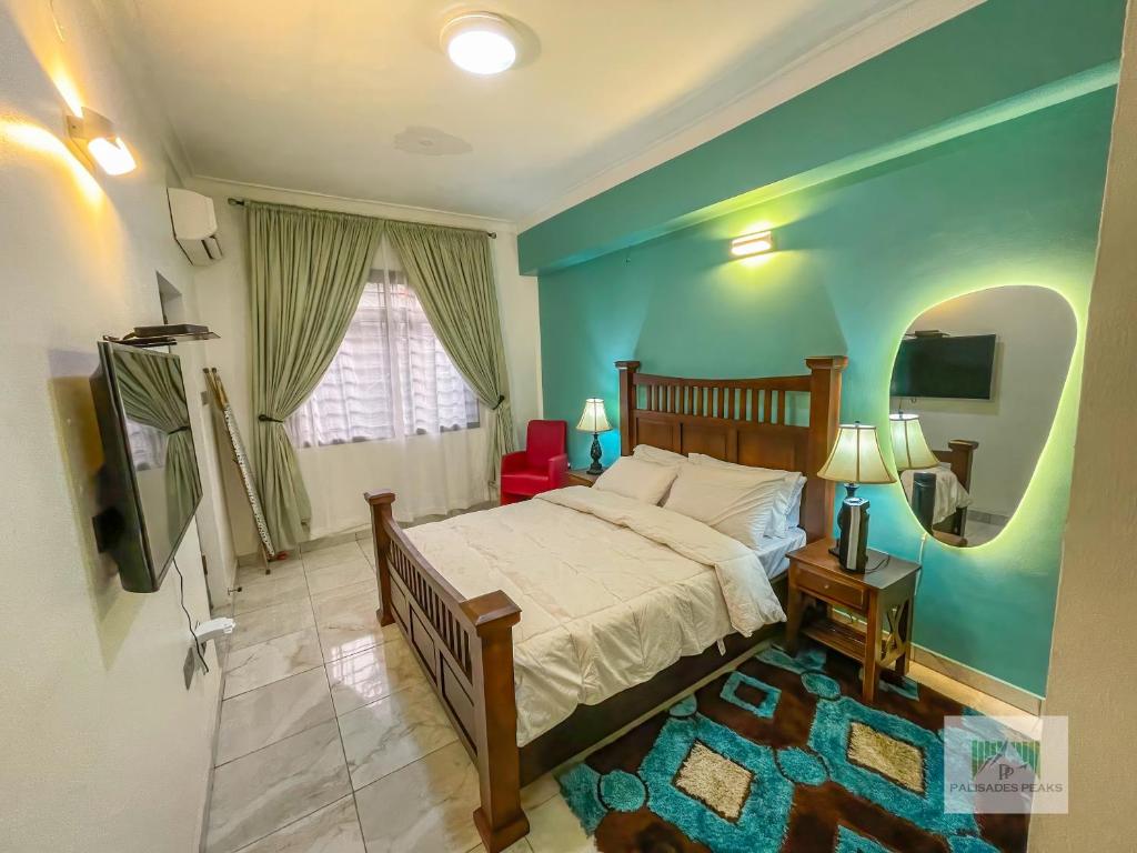 a bedroom with a bed and a blue wall at Palisades Peaks Luxury Apartments in Lekki