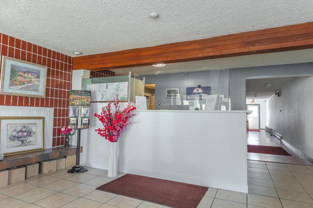 een lobby met een balie met een vaas met bloemen bij Canadas Best Value Inn Kelowna in Kelowna