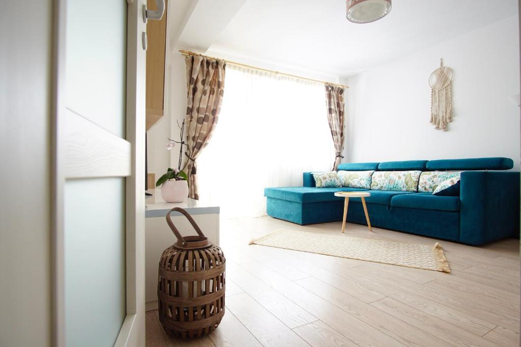 uma sala de estar com um sofá azul e uma mesa em Brates Apartment em Iaşi