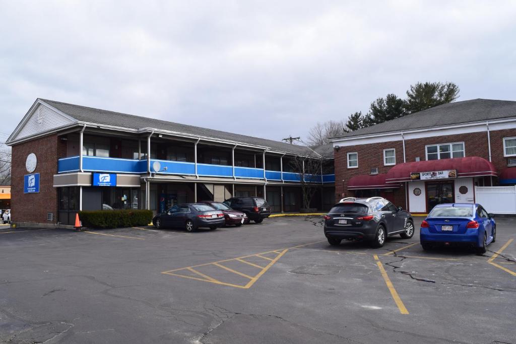 a parking lot with cars parked in front of a building at Framingham Inn in Framingham