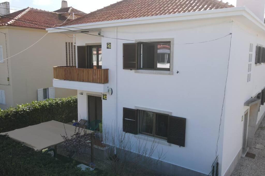 een wit huis met zwarte ramen en een balkon bij Hoso Beach House in Costa da Caparica