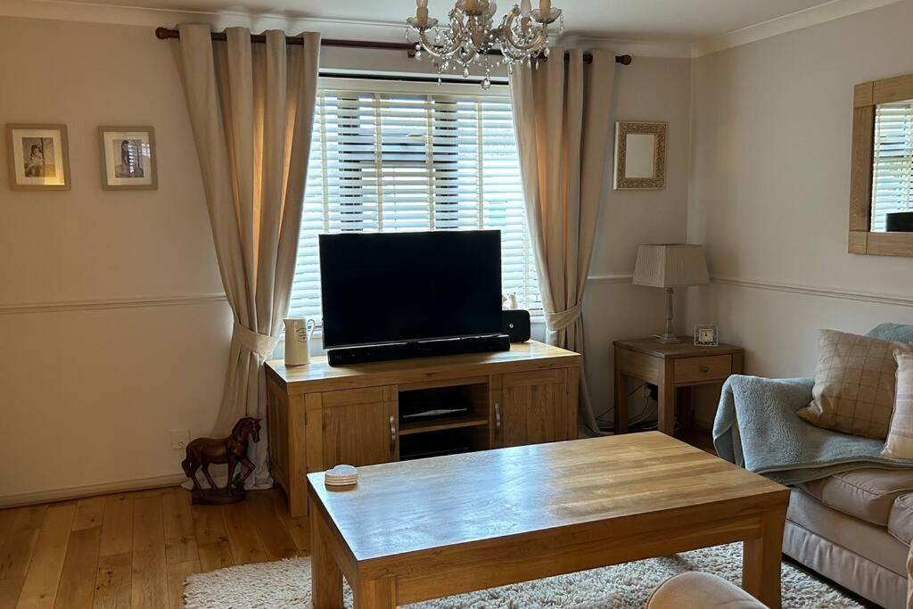 a living room with a flat screen tv on a wooden table at Cosy 2 bed, home from home in Haddenham