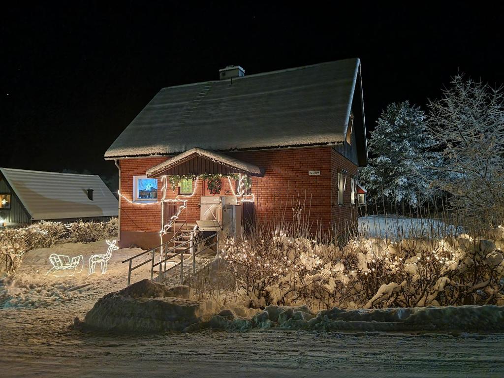 una pequeña casa de ladrillo rojo con porche por la noche en Cozy house in heart of Swedish Lapland en Vuollerim