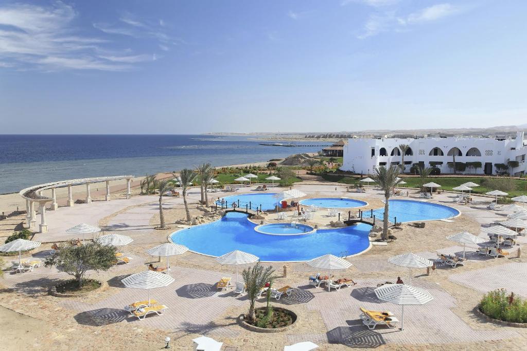 Three Corners Equinox Beach Resort في أبو دباب: اطلالة جوية على منتجع فيه مسبحين ومظلات