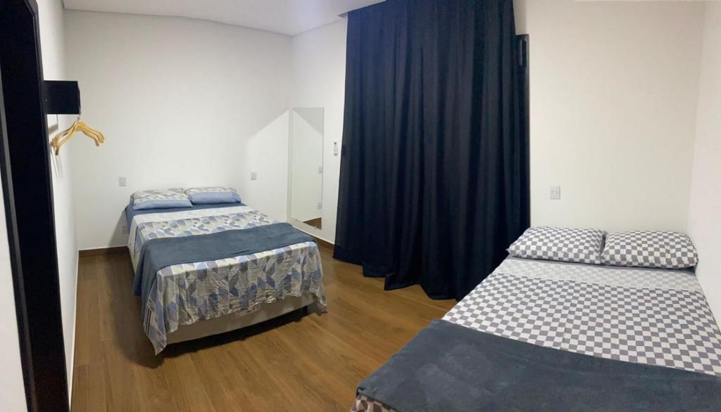 two beds in a room with blue curtains at Casa de Campo na Represa de Paranapanema Riviera de Sta Cristina XIII in Paranapanema