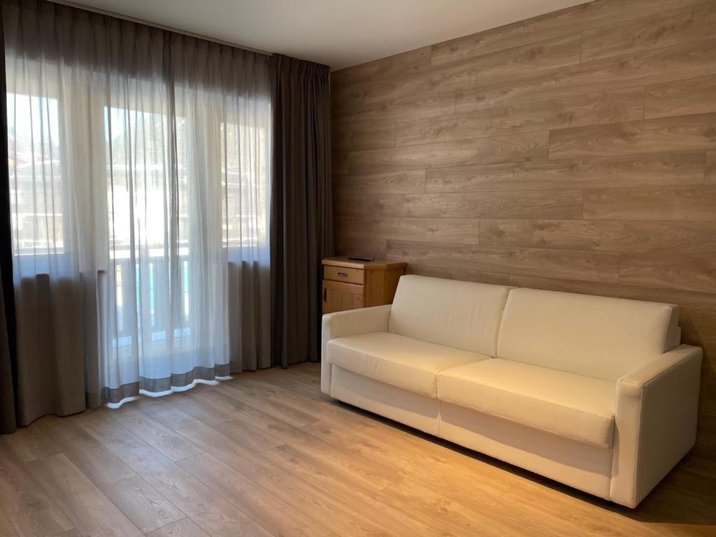 a living room with a white couch and window at Appartamento del rosengarten in Madonna di Campiglio