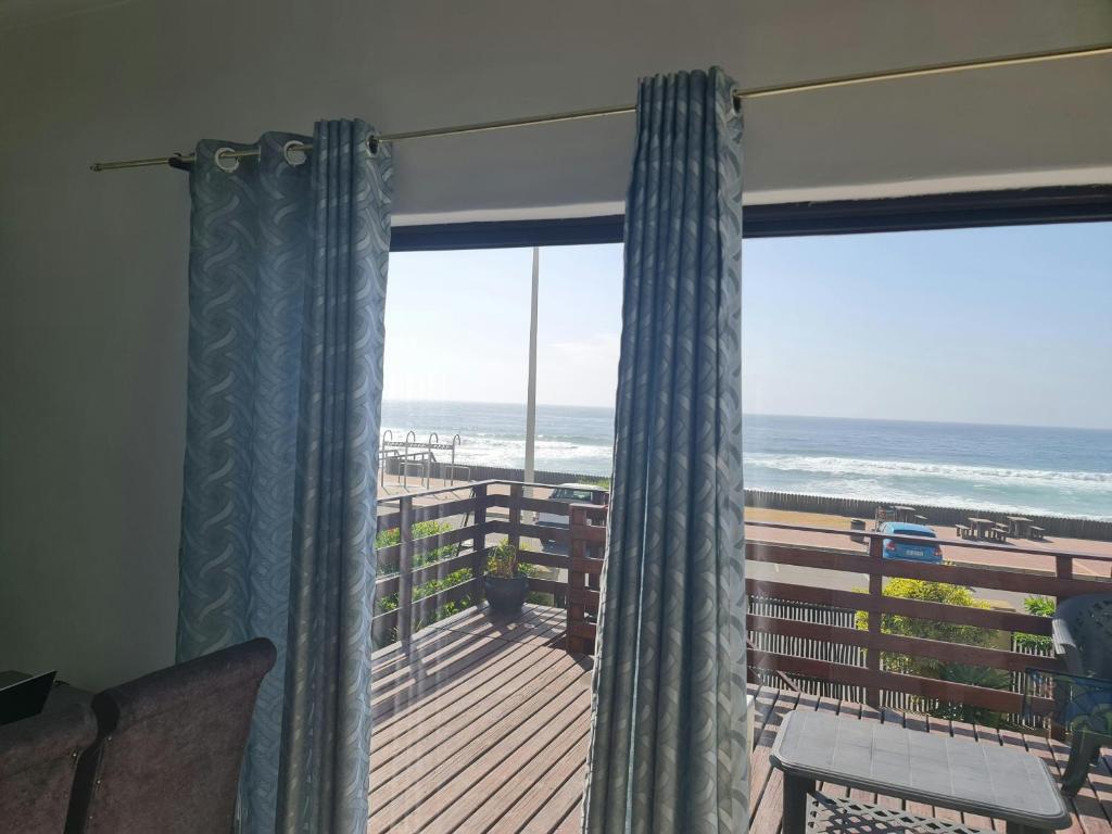 a room with a balcony with a view of the ocean at Oceans Breeze - Unit 2 Second floor in Durban