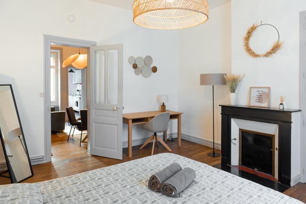 a bedroom with a bed and a desk and a fireplace at Appart chaleureux face gare in Limoges