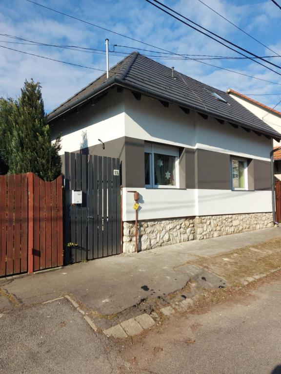 a house with a black gate and a fence at Regina Vendégház Miskolc in Miskolc