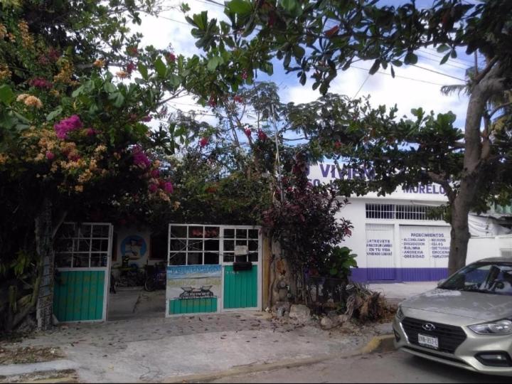 a car parked in front of a building with flowers at Buenos D&iacute;as Guest House in Puerto Morelos