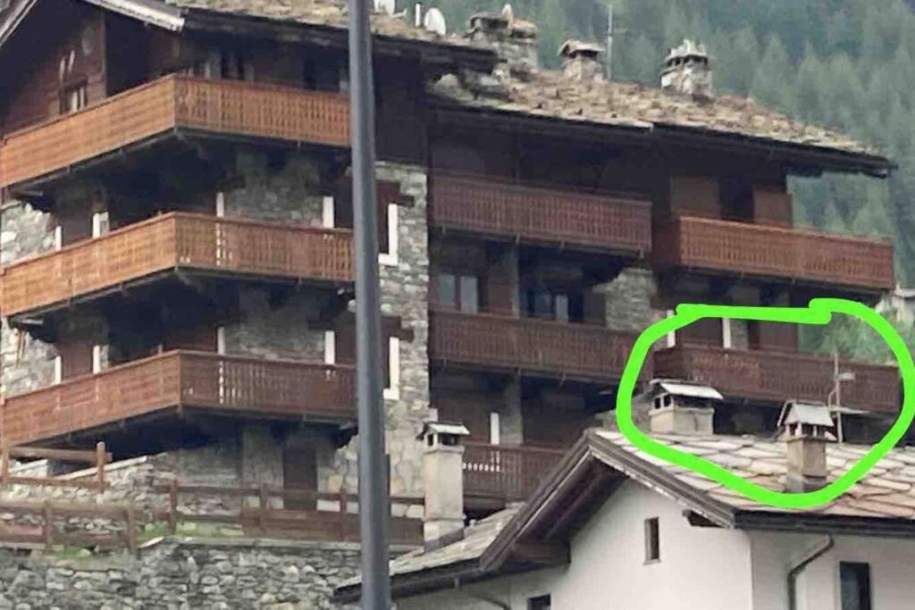 una freccia verde che punta verso un grande edificio di appartamento valtournenche il nido a Valtournenche