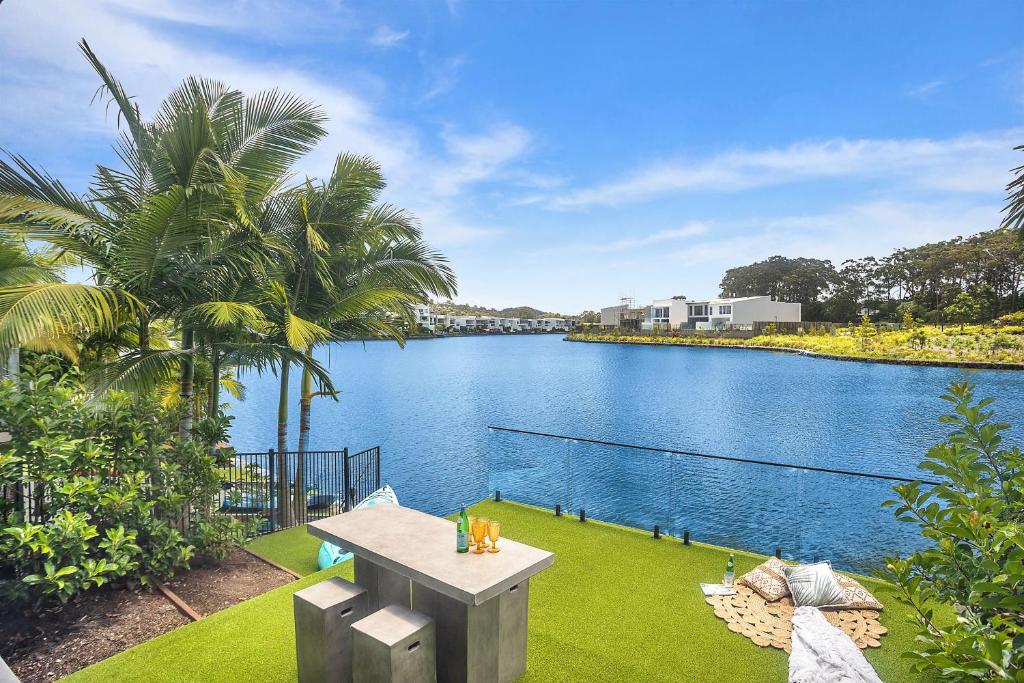 - une vue sur une étendue d'eau avec une table sur l'herbe dans l'établissement Executive, modern waterfront house, à Maroochydore