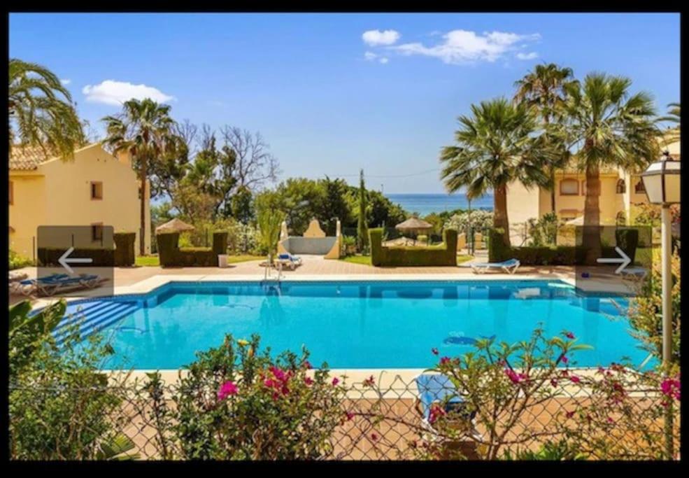 una gran piscina con palmeras y el océano en Appartement la Cala de Mijas toegang tot strand, en Mijas