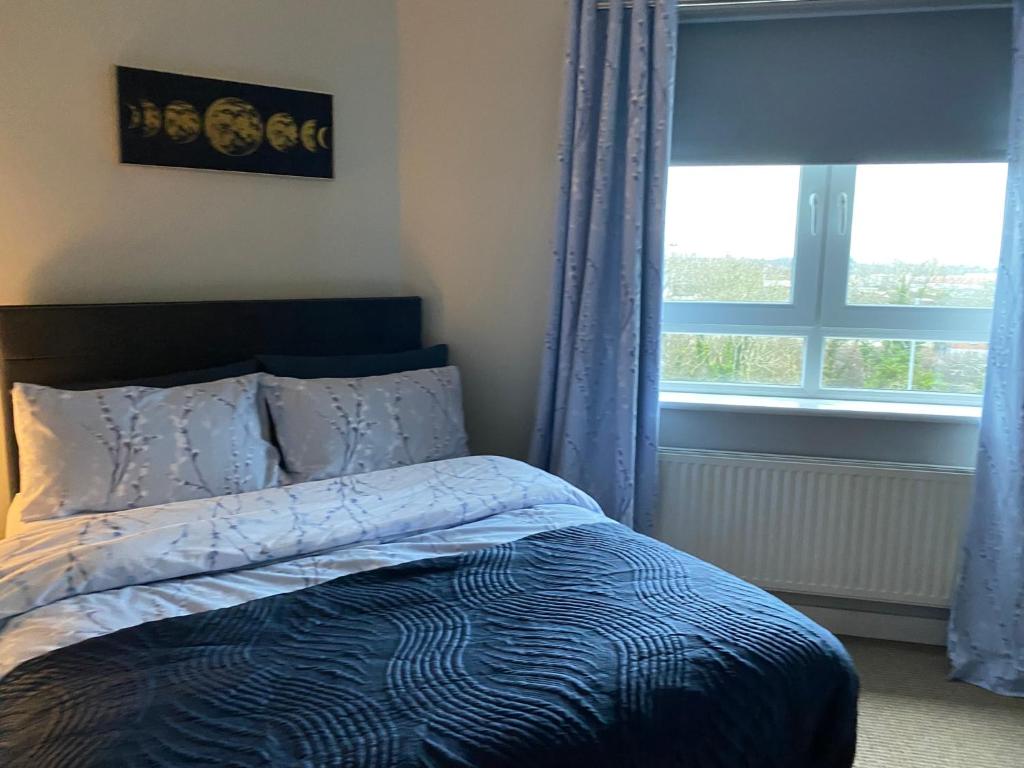 1 dormitorio con 1 cama con cortinas azules y ventana en Hastings Apartments Extra Large Self Catering Apt Tourism Certified Free Parking WiFi en Belfast