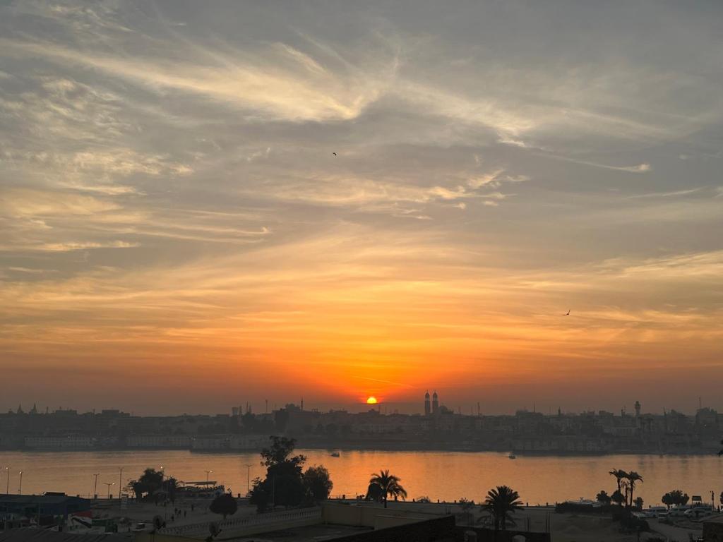 a sunset over a body of water with a city at Comfy Apartments in Harmony House - Nile View in Luxor