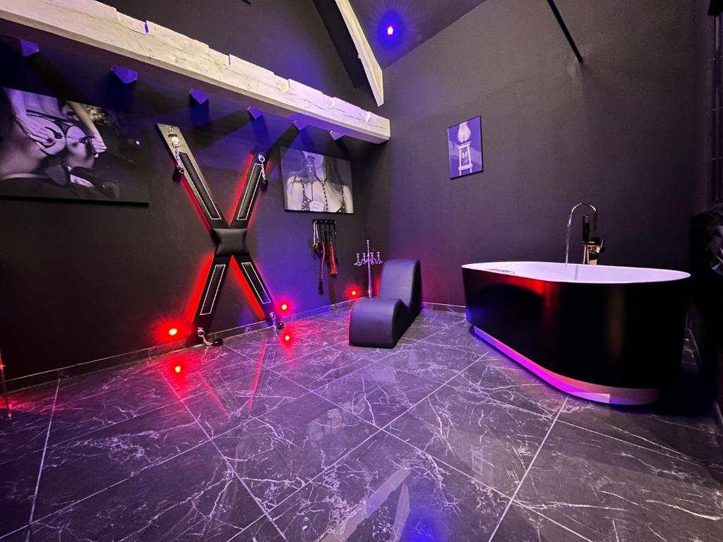 La salle de bains est pourvue d'une baignoire et de lumières rouges. dans l'établissement Loveroom de luxe - Thème 50 nuances de grey maison privative spa insolite, à Douchy-les-Mines