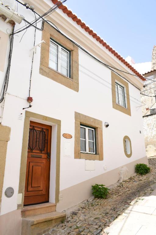 a white house with a wooden door on a street at Casa das Gémeas - Moradia rústica in Castelo de Vide