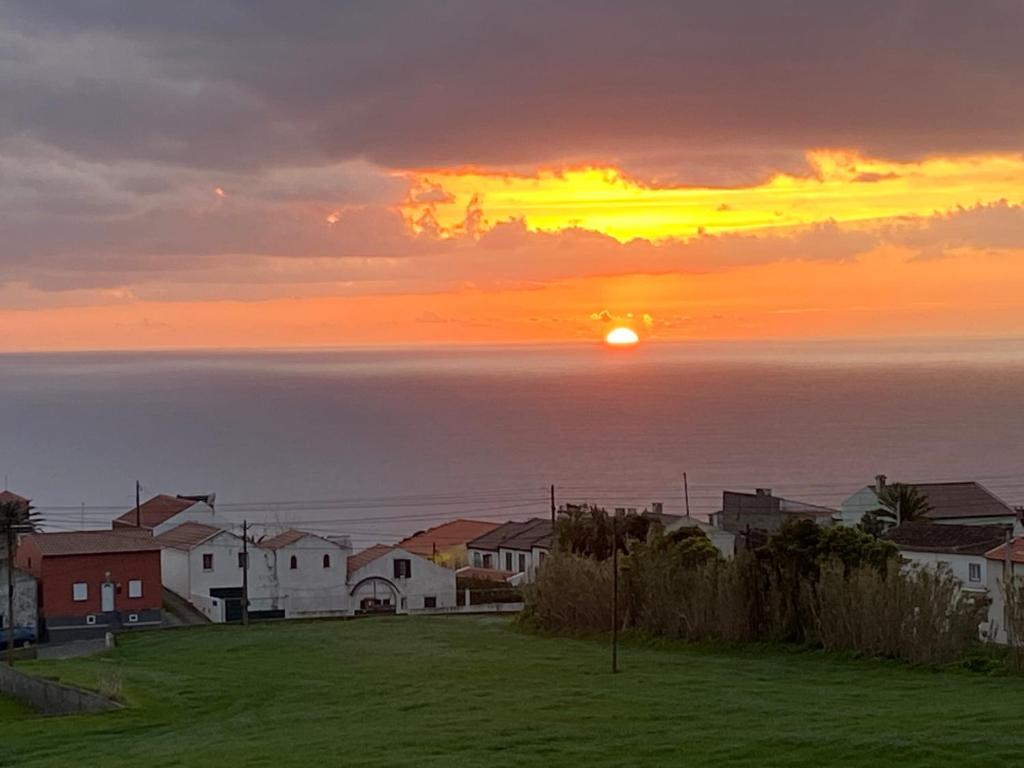 una puesta de sol sobre un pequeño pueblo con el océano en Green Tropical House, en Ponta Delgada