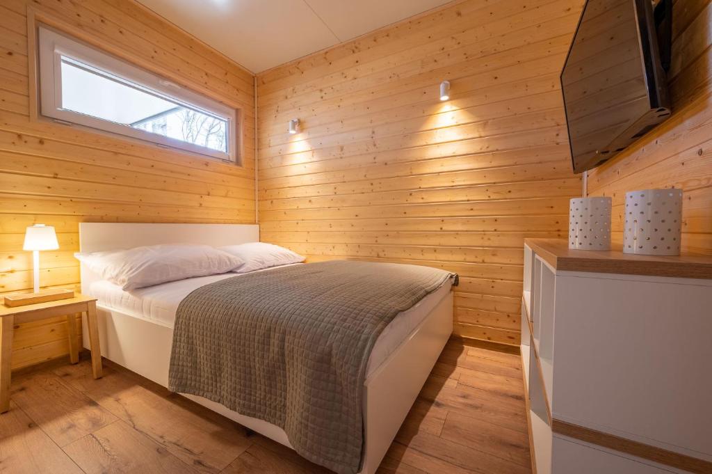 um quarto com uma cama numa parede de madeira em Darłowo Beach Houses em Darlowko