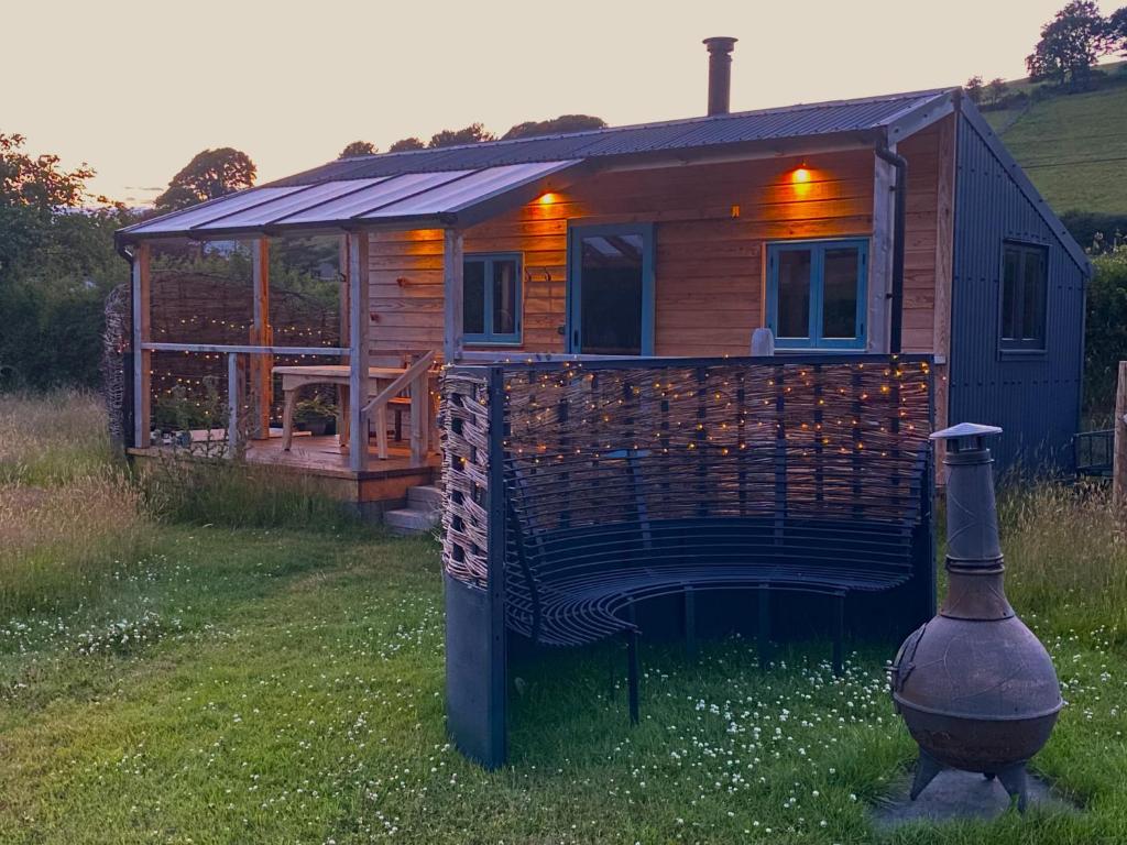 a wooden cabin with a large deck and a fire hydrant at Dôl Swynol Glamping Luxury cabin with outdoor bath in Aberystwyth