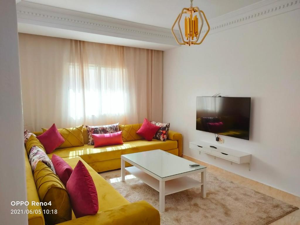 een woonkamer met een gele bank en een tafel bij Appartement Jawharat Mogador in Essaouira