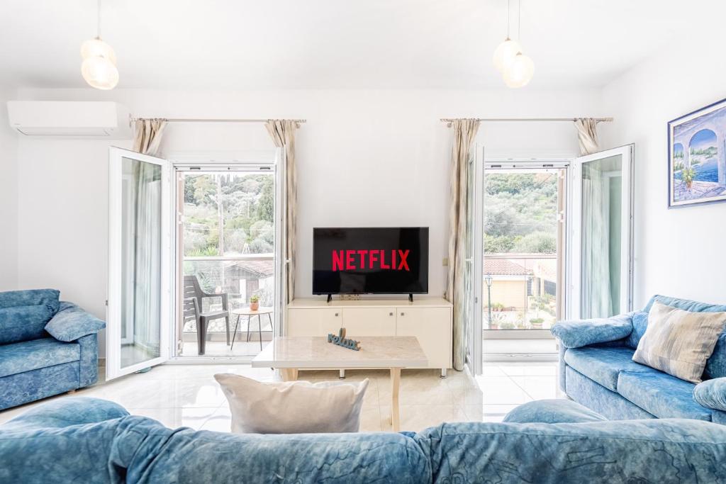 a living room with two blue couches and a tv at 4You Luxury Apartments by Keyplanner in Moraitika