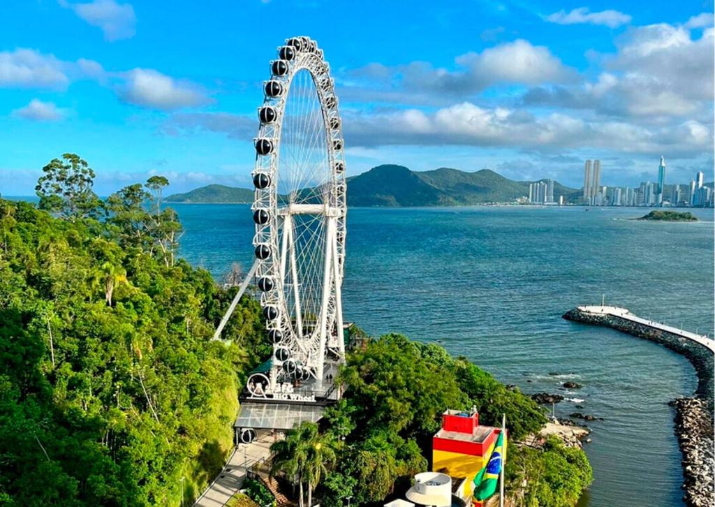 a large ferris wheel in the middle of the water at Studio de frente para o mar em Balneário Camboriú in Balneário Camboriú