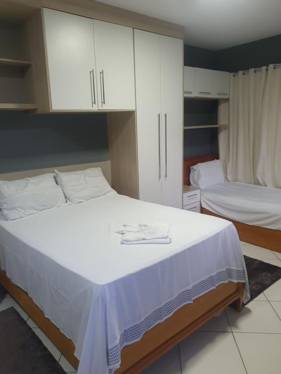 a bedroom with two beds and white cabinets at SUÍTE PRAIA DE ITAPARICA in Vila Velha