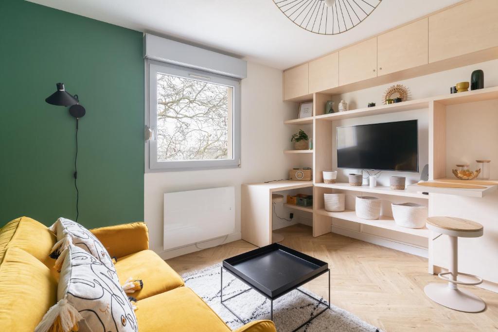 uma sala de estar com um sofá amarelo e uma televisão em Studio refait à neuf avec Parking en Bord de Loire em Nantes