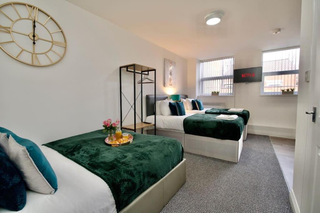 a bedroom with two beds and a clock on the wall at Swan Studio Three - Coventry in Coventry