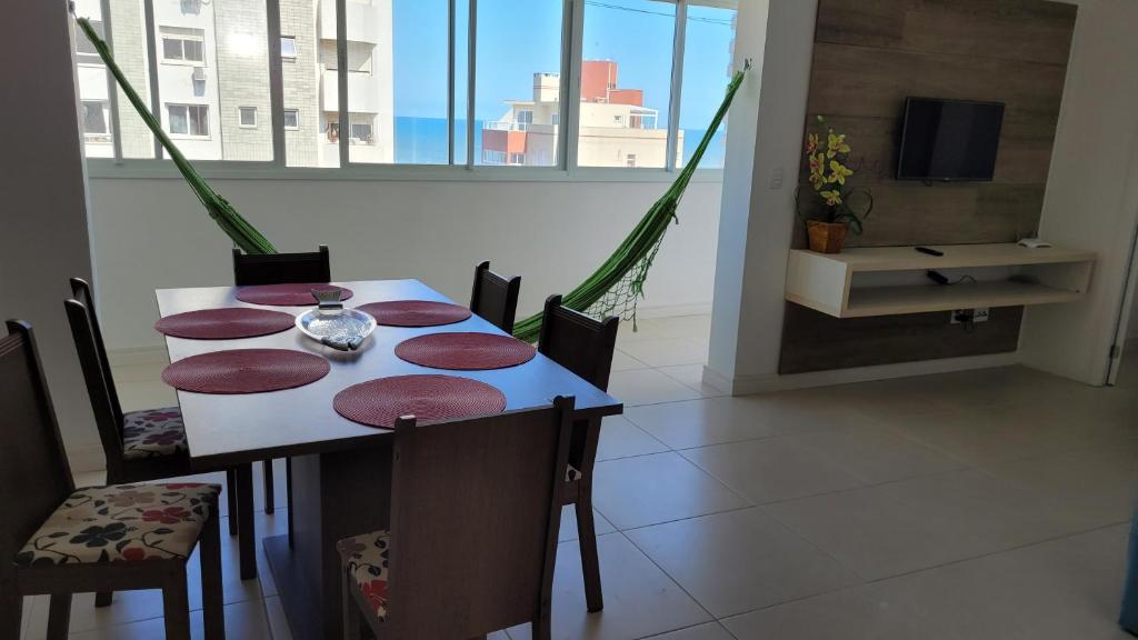 un comedor con mesa y sillas en una habitación en Praia Grande (12) - 3 quartos - 1 quadra Mar, en Torres