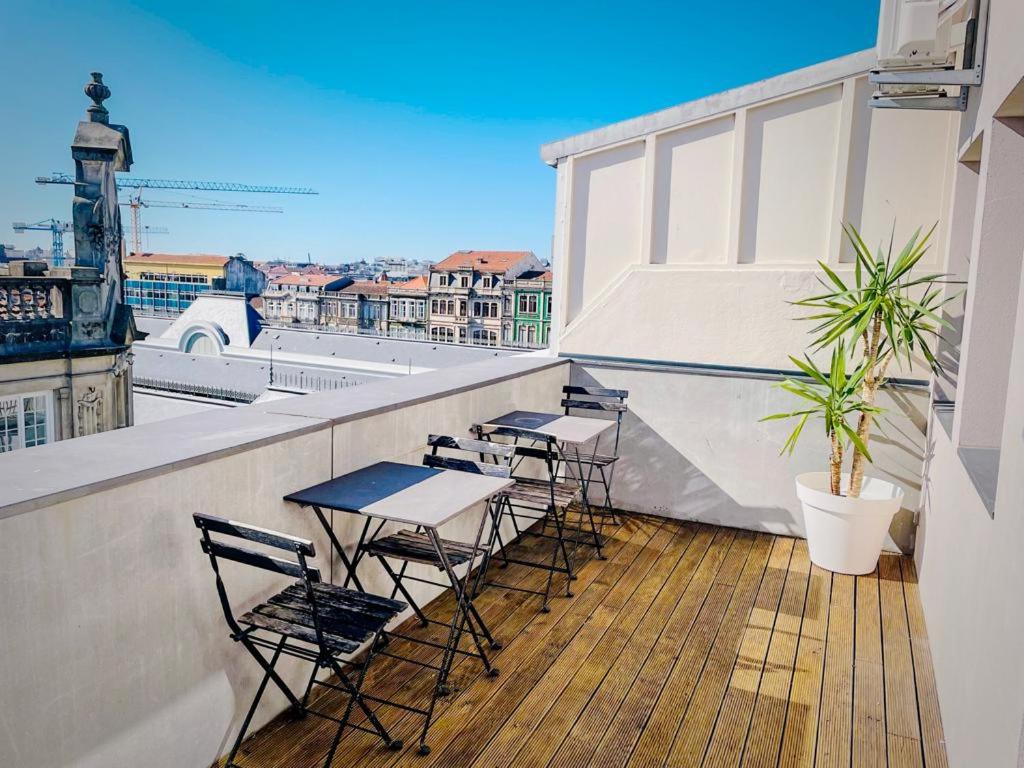 uma varanda com mesas e cadeiras num edifício em Baixa24 - Bolhão Apt with Sunset Rooftop no Porto
