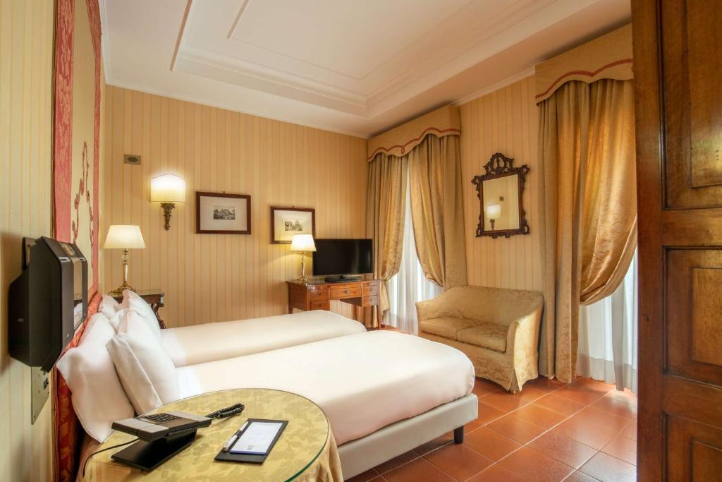 ローマにあるHotel Canada, BW Premier Collectionのベッドと椅子付きのホテルルーム